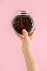 Arms raised up holding coffee cup on pink background.