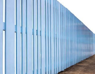 Isolate, side view, an old wooden fence painted in a beautiful blue color, which stretches over a concrete floor to surround a house.