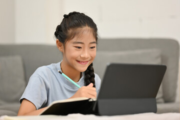 Little student girl using tablet for education and learning at home.