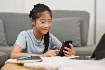 Asian little school girl using tablet and smartphone for studying online classes at home, Online learning, E-learning, Distance learning, online education concept.