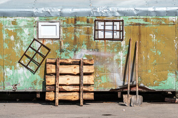 old workers shelter trailer construction and pair shovels near aged wall