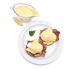 Tasty eggs Benedict with hollandaise sauce and bacon isolated on white background