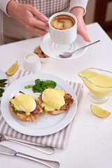 Tasty eggs Benedict, hollandaise sauce and aspargus covered with bacon