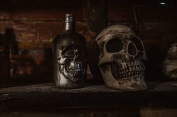 An old glass bottle stands on a dark shelf in the hold of the ship next to the skull.