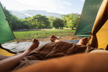 Two people lying in tent with a view of forest and mountains.