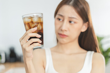Avoid, limits sweet sugar, choose asian young woman, girl holding, looking at a glass of cold cola soft drink soda, sparkling water with ice by her hand. Health care, healthy diet lifestyle concept.