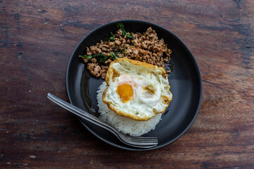 Stir fried Thai basil with minced pork and a fried egg on black plate