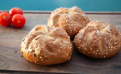 Fresh buns with seed and cherry tomatoes on cutting board.