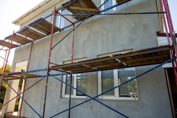 Modern repair and reconstruction of the house. Insulation of the house with polystyrene foam, plastering, applying plaster and painting facade walls using scaffolding when repairing the house.