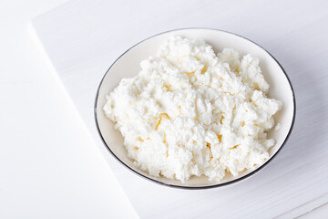 White porcelain bowl with grainy cottage cheese isolated on a white background