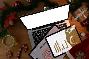 Above view of laptop computer, digital tablet, document and Christmas decorations on wooden table