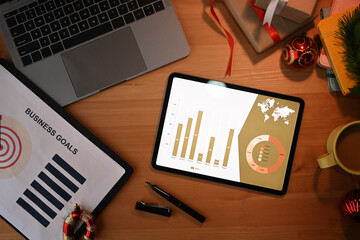 Top view digital tablet, laptop and Christmas decorations on wooden office desk