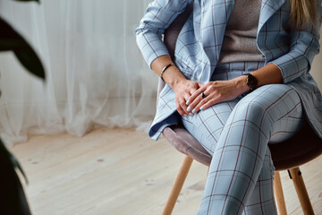 Fototapeta premium Hands of an unrecognizable woman in a suit sitting on a chair