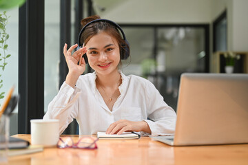 Happy young woman wearing wireless headphone having learning online at virtual class on laptop computer. E-learning education concept