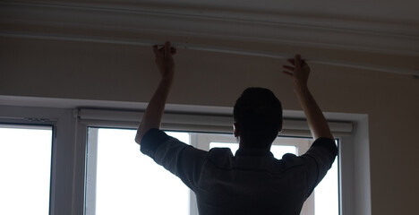 A handyman installing new cornice for curtains, home repair and renovation works
