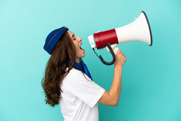 Airplane stewardess woman isolated on blue background shouting through a megaphone
