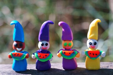 Figures of colorful dwarfs hold watermelons in their hands and smile. Positive mood. The emotion of joy.