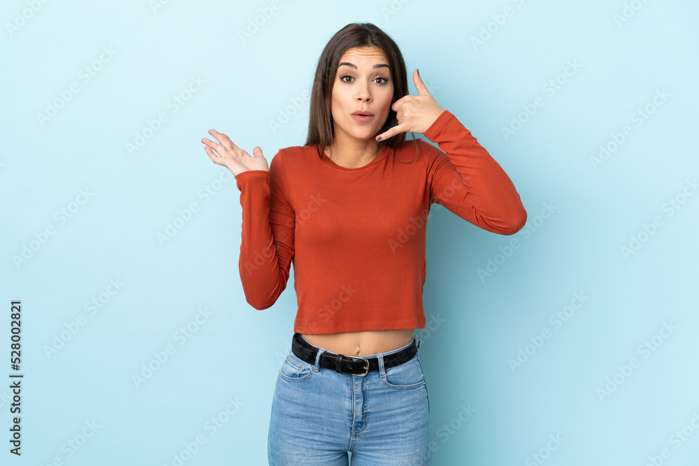 Sticker Young caucasian woman isolated on blue background making phone gesture and doubting