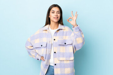 Young caucasian woman isolated on blue background showing ok sign with fingers