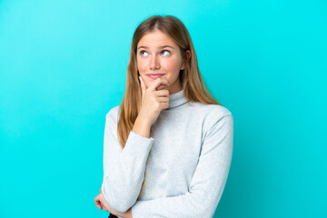 Young blonde woman isolated on blue background thinking an idea while looking up