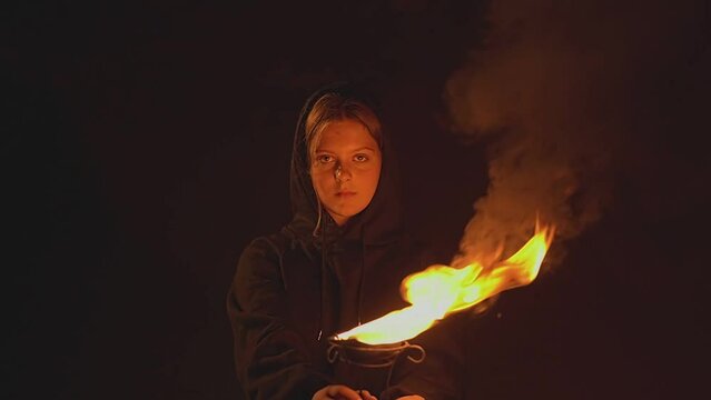 girl in a black sweatshirt holding a bowl of fire