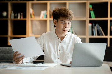 A man sits in the office of a startup company, he is an employee working in the marketing department, planning marketing to grow the company. Concept of working in a startup company office.