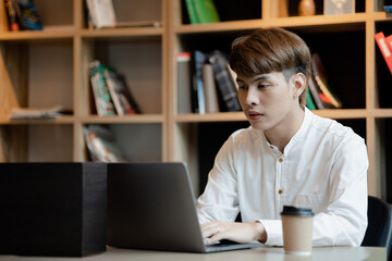 A man sits in the office of a startup company, he is an employee working in the marketing department, planning marketing to grow the company. Concept of working in a startup company office.