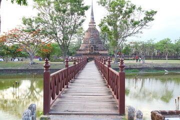 Wooden red bridge. Cross a pond to the temple in Sukhothai Historical Park, Thailand