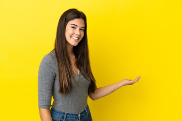 Young Brazilian woman isolated on yellow background extending hands to the side for inviting to come