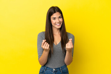 Young Brazilian woman isolated on yellow background making money gesture