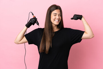 Tattoo artist woman isolated on pink background doing strong gesture