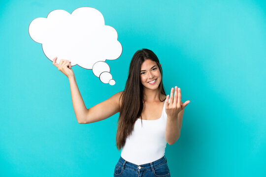 Young Brazilian woman isolated on blue background holding a thinking speech bubble and doing coming gesture