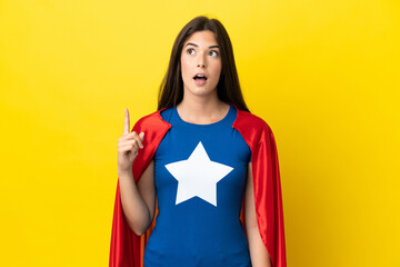 Super Hero Brazilian woman isolated on yellow background thinking an idea pointing the finger up