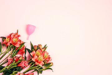 Menstrual cup with alstroemeria flowers on pink background. Women's health, hygiene concept.