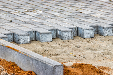 Pavement repairs and paving slabs laying on the prepared surface, with tile cubes in the background. Laying paving slabs in the pedestrian zone of the city. Paving slabs and curbs.