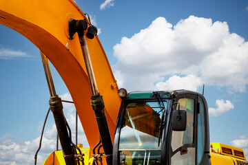 Backlit excavator on an industrial site against the background of the evening sky. Construction machinery for earthworks.