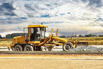 Road grader at the construction site. Powerful construction machine for ground leveling and excavation. Close-up. Professional construction equipment.