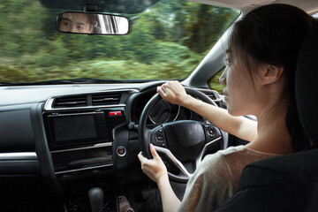 Happy Asian woman driving a car and smiling. Cute young success happy brunette woman is driving a car. Portrait of happy female driver steering car with safety belt