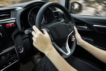 Obraz premium Happy Asian woman driving a car and smiling. Cute young success happy brunette woman is driving a car. Portrait of happy female driver steering car with safety belt