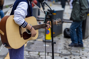 Busker. Singer guitarist street musician with acoustic guitar. Close up with selective focus on...