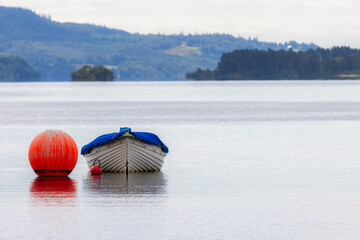 Empty rowing boat floating on lake at Loch Lomond Scotland. Calming landscape image.