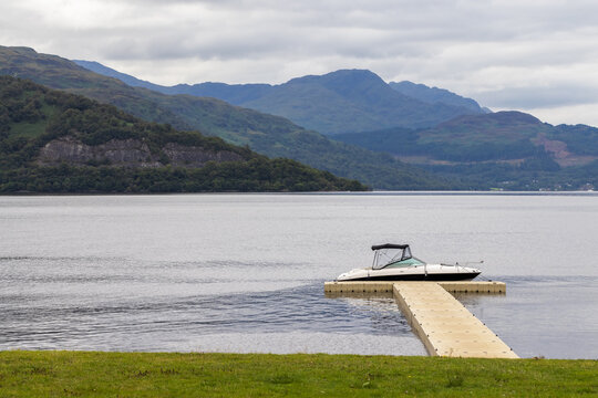 Idyllic lake front mooring. Small boat moored on a Loch in Scotland UK. Calm landscape.