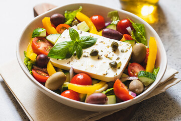 Classic Greek salad of fresh cucumber, tomato, sweet pepper, lettuce, red onion, feta cheese and olives with olive oil.