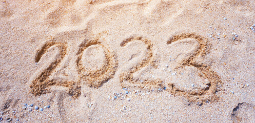 New Year 2023. Figures on the sandy shell seashore.