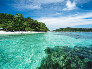 Fototapeta na wymiar Scenic view of Koh Dong Island white sand beach and crystal clear turquoise sea water with coral reef against summer blue sky. Near Koh Lipe Island, Tarutao National Marine Park, Satun, Thailand.