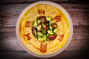 Homemade hummus with tahini plate with olive oil, parsley and paprika isolated on brown background. High quality photo