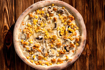 Appetizing pizza on a creamy sauce with mushrooms, corn, chicken fillet and mozzarella cheese on woden background