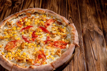 Pizza for children on a cream base with chicken fillet, tomatoes, corn and mozzarella cheese on wood background