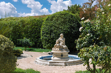 Garden sculpture - a dried (neglected) fountain with a beautiful woman and child on the paths