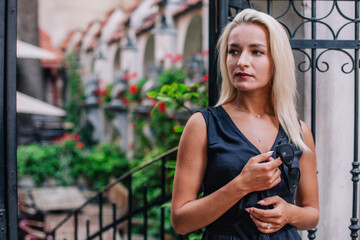 A young, blonde girl in a black blouse and sunglasses poses against the backdrop of an old courtyard in Lviv. Ukraine.